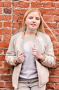 Beautiful blonde girl posing near a brick wall