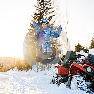 Beautiful blonde girl with red ATV in winter in the mountains