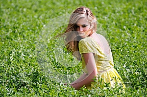 Beautiful blonde girl sitting in a meadow