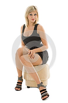 Beautiful blonde girl is sitting on an ottoman