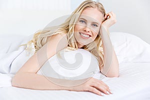 beautiful blonde girl smiling at camera while lying