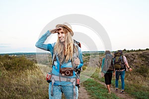 Beautiful blonde girl smiling, looking into distance, friends tourists background.