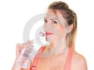 Beautiful blonde girl in sport clothes holding water bottle after workout isolated on white studio background