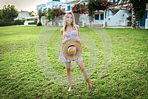 Beautiful blonde girl on summer vacation, spring break in a flower dress, green meadow,  lawn