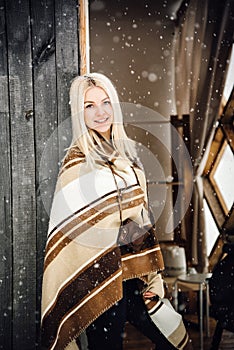 Beautiful blonde girl with a vintage camera smiling on a wooden wall background