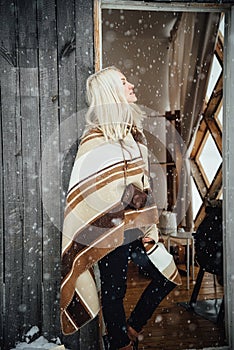 Beautiful blonde girl with a vintage camera smiling on a wooden wall background