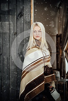 Beautiful blonde girl with a vintage camera smiling on a wooden wall background