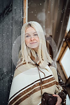 Beautiful blonde girl with a vintage camera smiling on a wooden wall background