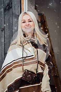 Beautiful blonde girl with a vintage camera smiling on a wooden wall background