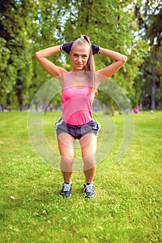 Beautiful blonde girl working out in park doing squats