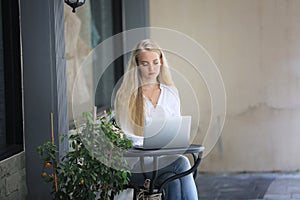 Beautiful blonde hair girl sitting with laptop in front of retails shop,Small business owner concept. photo
