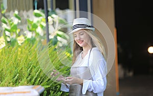 Beautiful blonde hair girl standing with confidence in front of flower in open retails flora shop. Small business owner concept photo