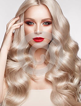 Beautiful blonde in a Hollywood manner with curls, natural makeup and red lips. Beauty face and hair.