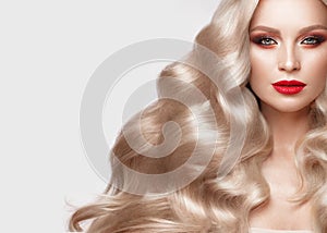 Beautiful blonde in a Hollywood manner with curls, natural makeup and red lips. Beauty face and hair.