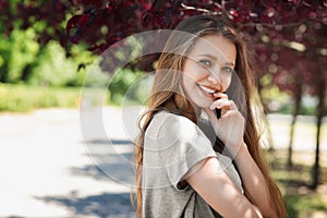 A beautiful blonde on a light sunny background. An adorable girl relaxing and laughing outdoors. A posing young woman in a park.