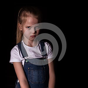 Beautiful blonde little girl on a dark background. She stands in different poses and shows different emotions. free