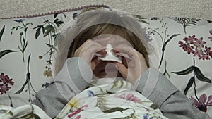 Beautiful blonde little girl is sick, blows her nose, cough.