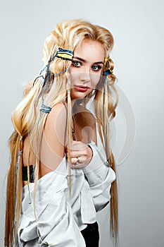 Beautiful blonde with long hair, unusual hairstyle with colorful threads, on white background