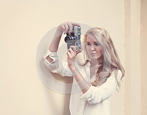 Beautiful blonde with long hair with vintage camera in hand, warm, tonning