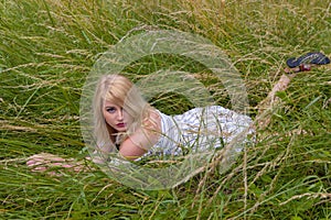 Beautiful blonde lying in grass field