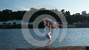 Beautiful blonde mom and daughter run towards each other on the river Bank at sunset.