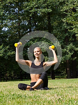 The beautiful blonde in park with dumbbells