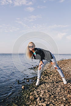 Beautiful blonde in ripped jeans having fun on the shore of the blue sea