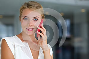 Beautiful blonde smiling businesswoman talk red cellphone