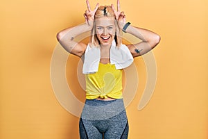 Beautiful blonde sports woman wearing workout outfit posing funny and crazy with fingers on head as bunny ears, smiling cheerful