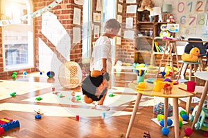 Beautiful blonde toddler playing with monkey mask standing around lots of toys at kindergarten