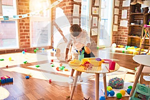 Beautiful blonde toddler playing with monkey mask standing around lots of toys at kindergarten