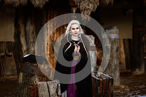 Beautiful blonde Viking dressed in a black cloak against the backdrop of the castle