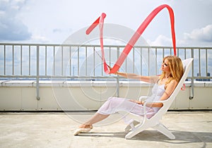 Beautiful blonde in white sitting on a lounger photo