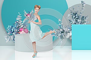 A beautiful blonde woman, adorned in a retro-style dress and hairdo, striking a pose in a studio adorned with flowers. Perfect for