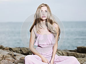 Beautiful blonde woman on the beach. Lady in pink dress