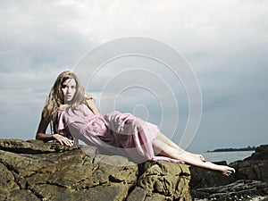Beautiful blonde woman on the beach. Lady in pink dress