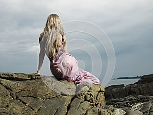 Beautiful blonde woman on the beach. Lady in pink dress