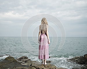 Beautiful blonde woman on the beach. Lady in pink dress