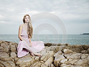 Beautiful blonde woman on the beach. Lady in pink dress