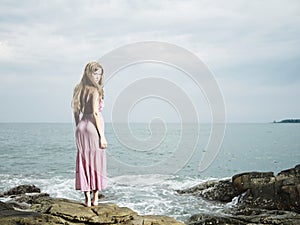 Beautiful blonde woman on the beach. Lady in pink dress