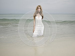 Beautiful blonde woman on the beach. Lady in white dress