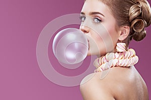 Beautiful blonde woman blowing pink bubble gum. Fashion portrait.