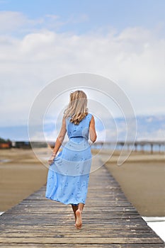 Beautiful blonde woman posing on an empty sea beach