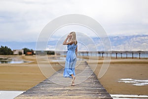 Beautiful blonde woman posing on an empty sea beach