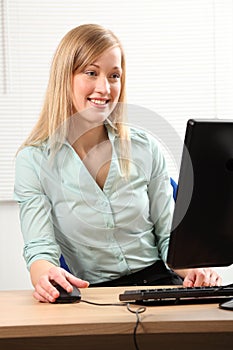 Beautiful blonde woman busy at office computer