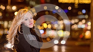 Beautiful, blonde woman in car lights in the night city.