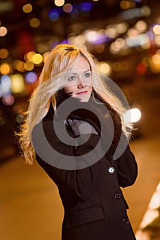 Beautiful, blonde woman in car lights in the night city.