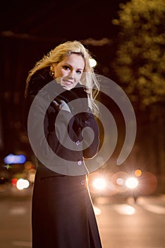 Beautiful, blonde woman in car lights in the night city.