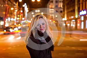 Beautiful, blonde woman in car lights in the night city.