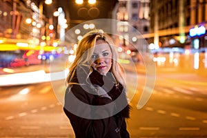 Beautiful, blonde woman in car lights in the night city.